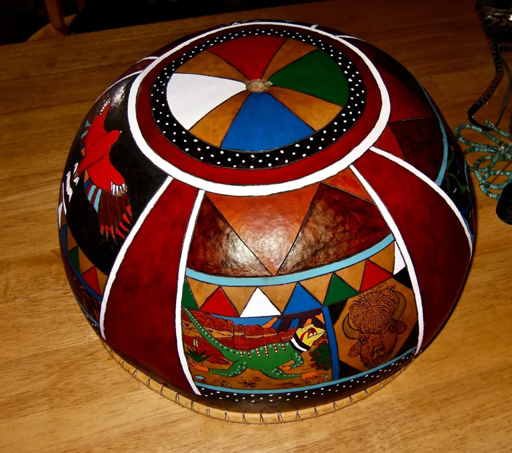 A red, white, and blue painted ball on a wooden table inspired by Ngoma music.