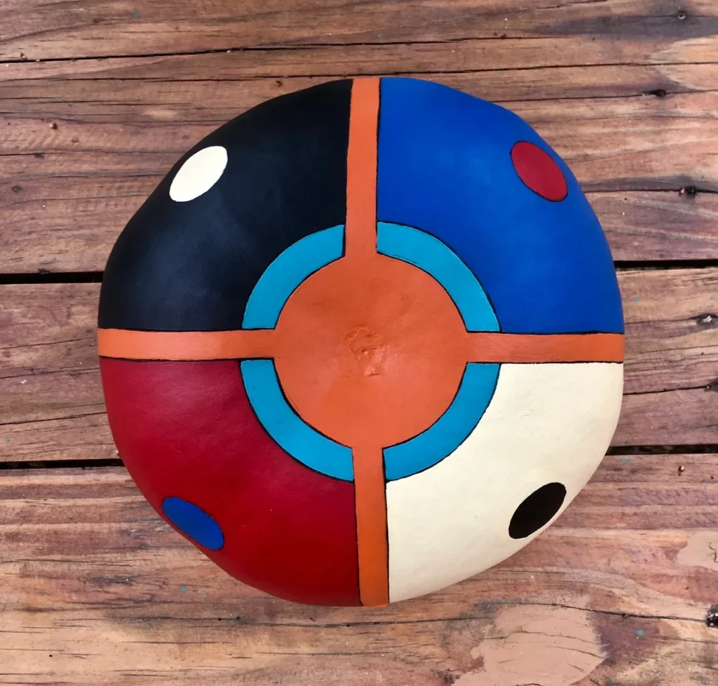 An African-inspired pillow in black, red, blue, and orange placed on a wooden table.