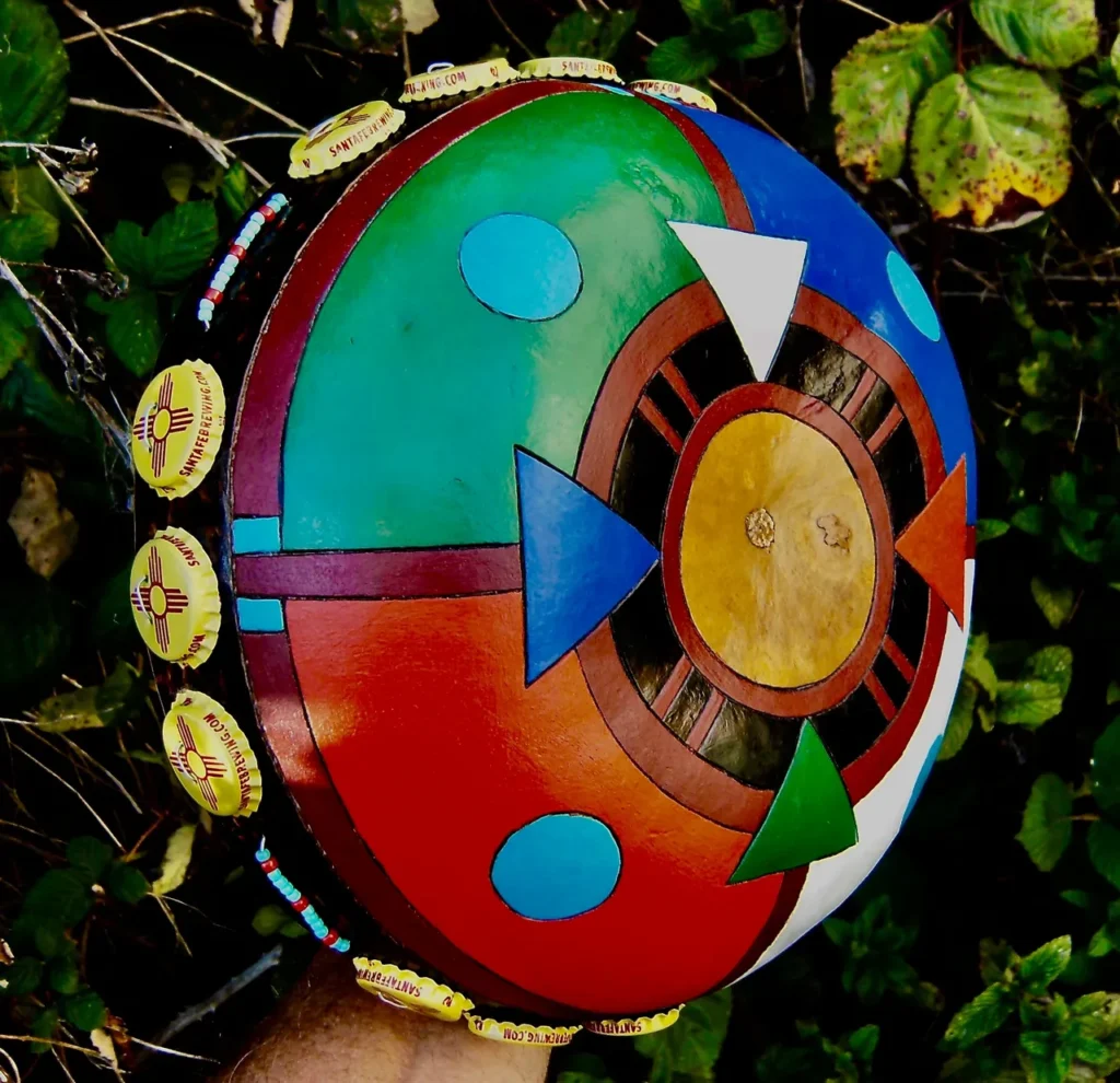 A vibrant Ngoma drum is cradled in a hand amidst lush grass.