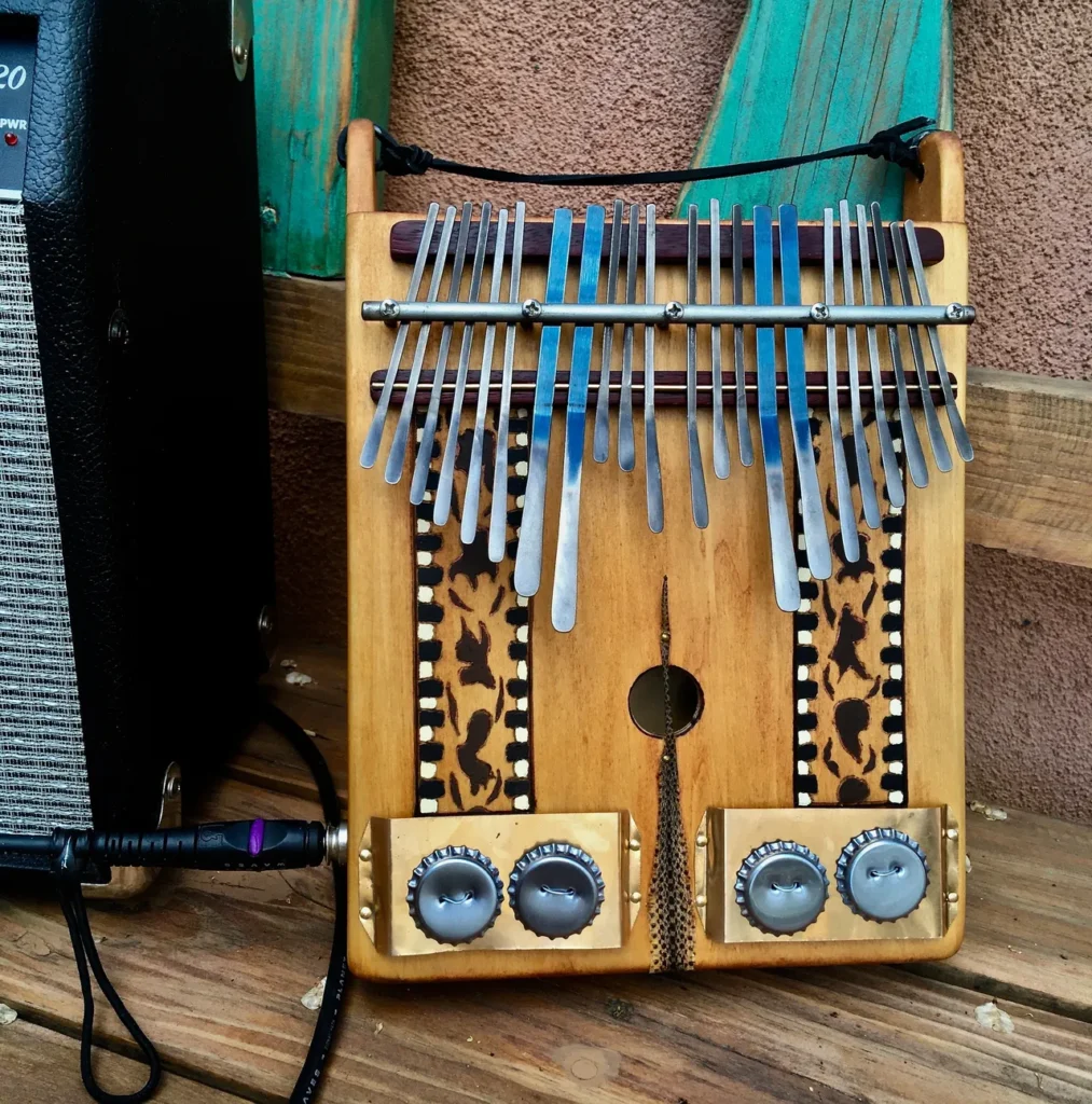 A wooden Lamellaphone instrument next to a speaker and amplifier.