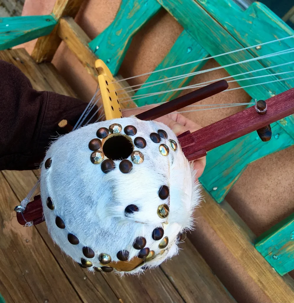 An individual playing an intricately carved ngoma, a traditional African musical instrument.