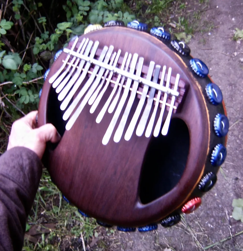 A person is holding an African harp made from a bottle cap ukulele.