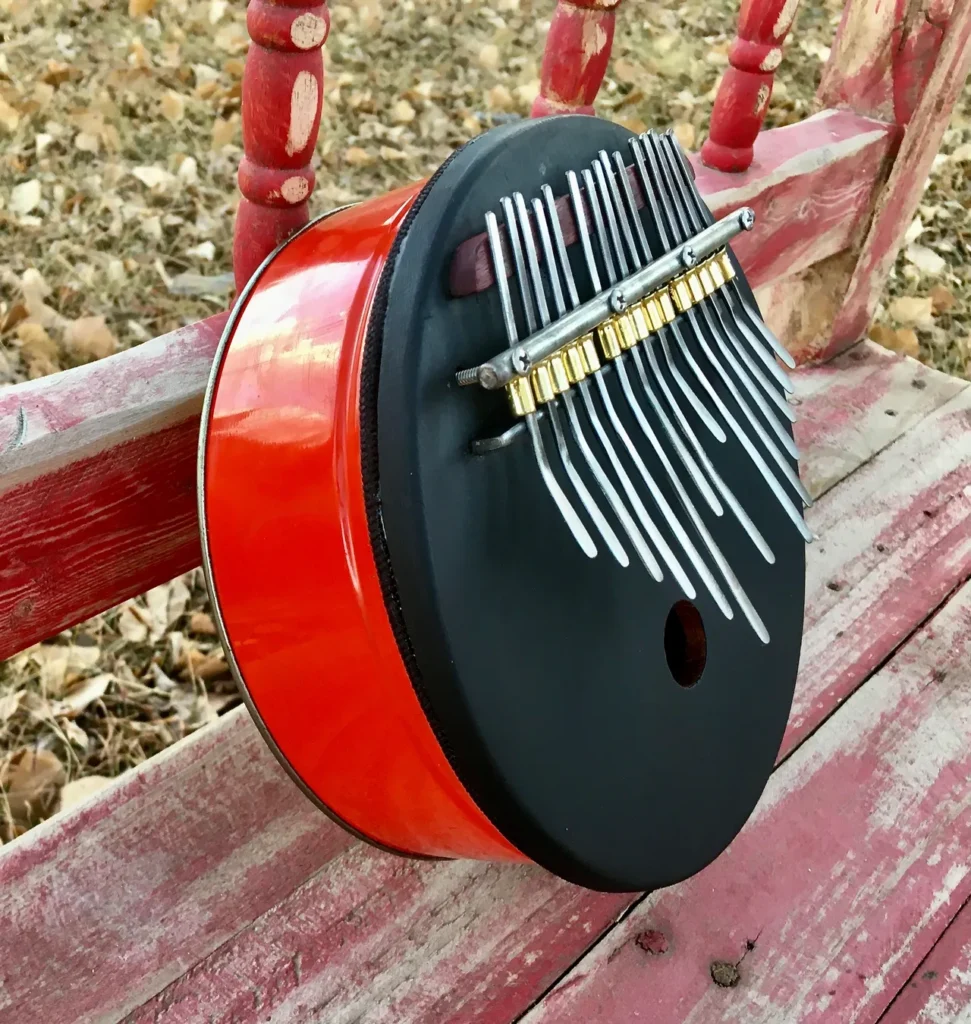 An African-inspired ukulele adorned with red and black colors, gracefully placed on a polished wooden bench.