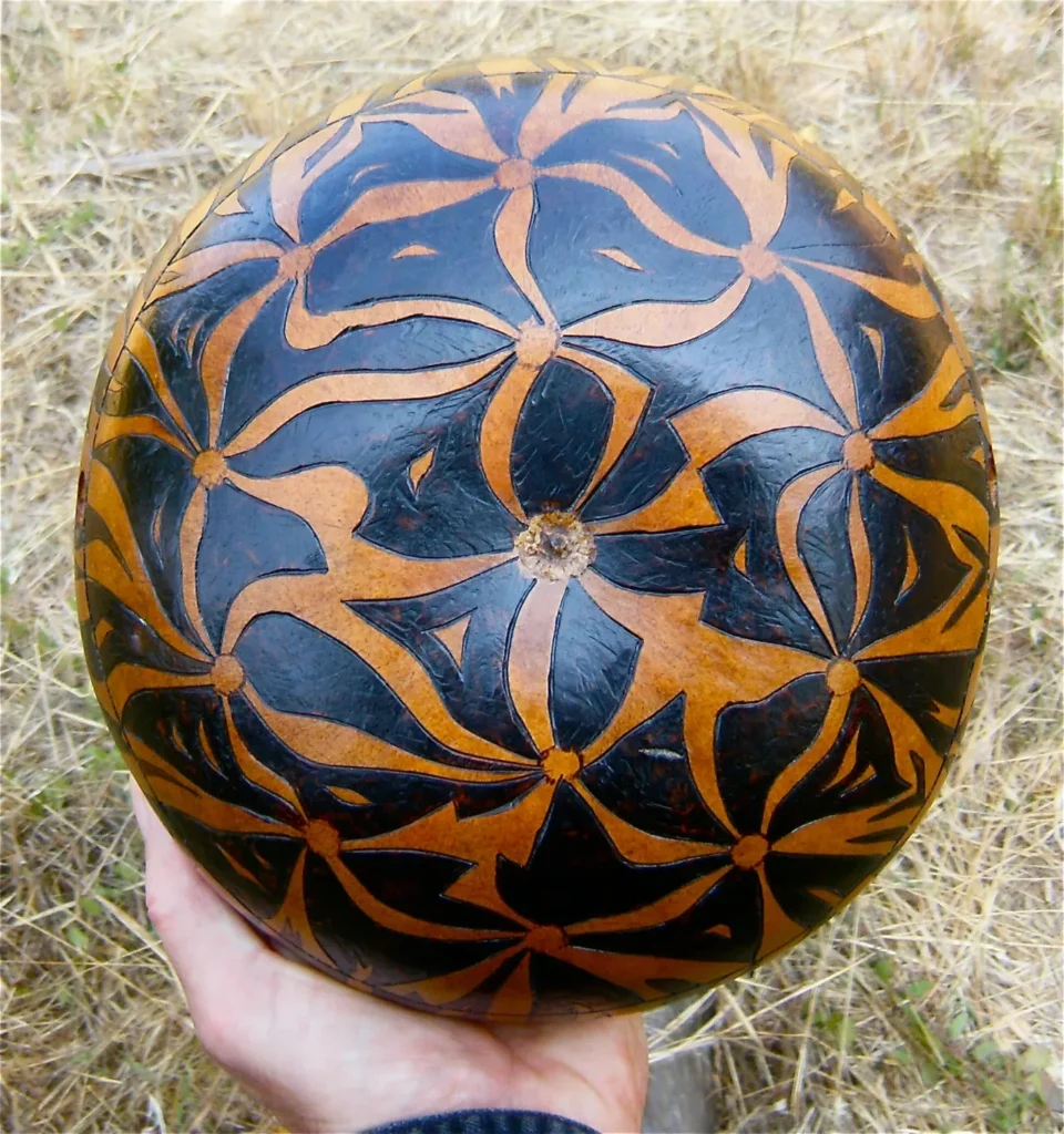 An Ngoma artist holding a black and brown carved pumpkin.