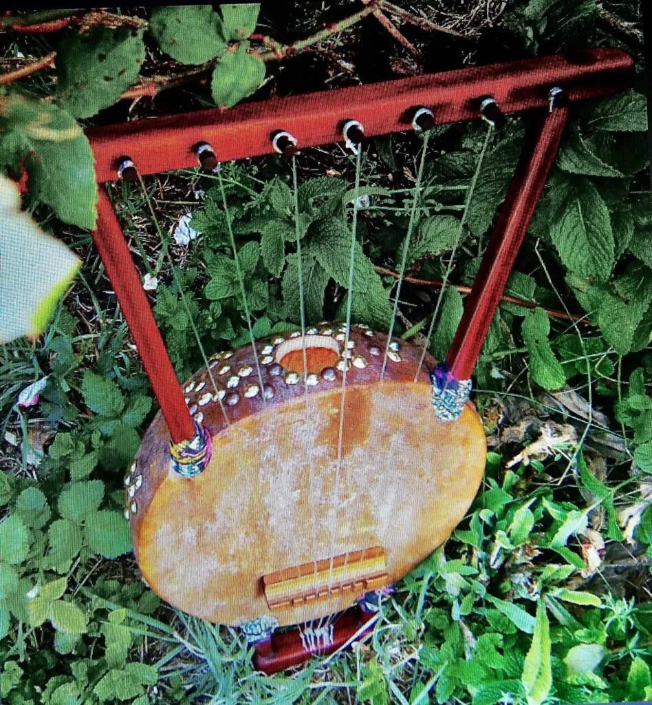 A wooden harp, resembling a Kalimba, peacefully rests amidst the green grass.