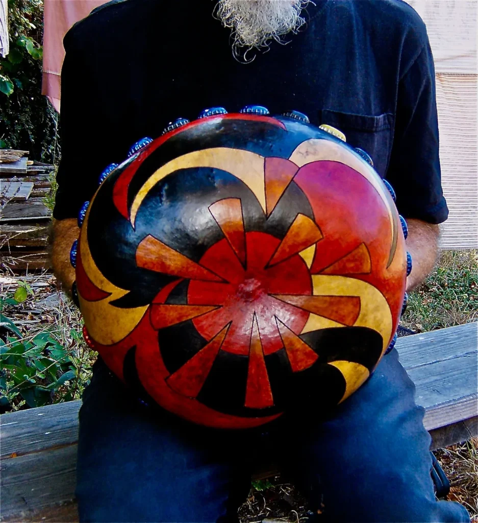 A man sitting on a bench holding an Ilimba drum.