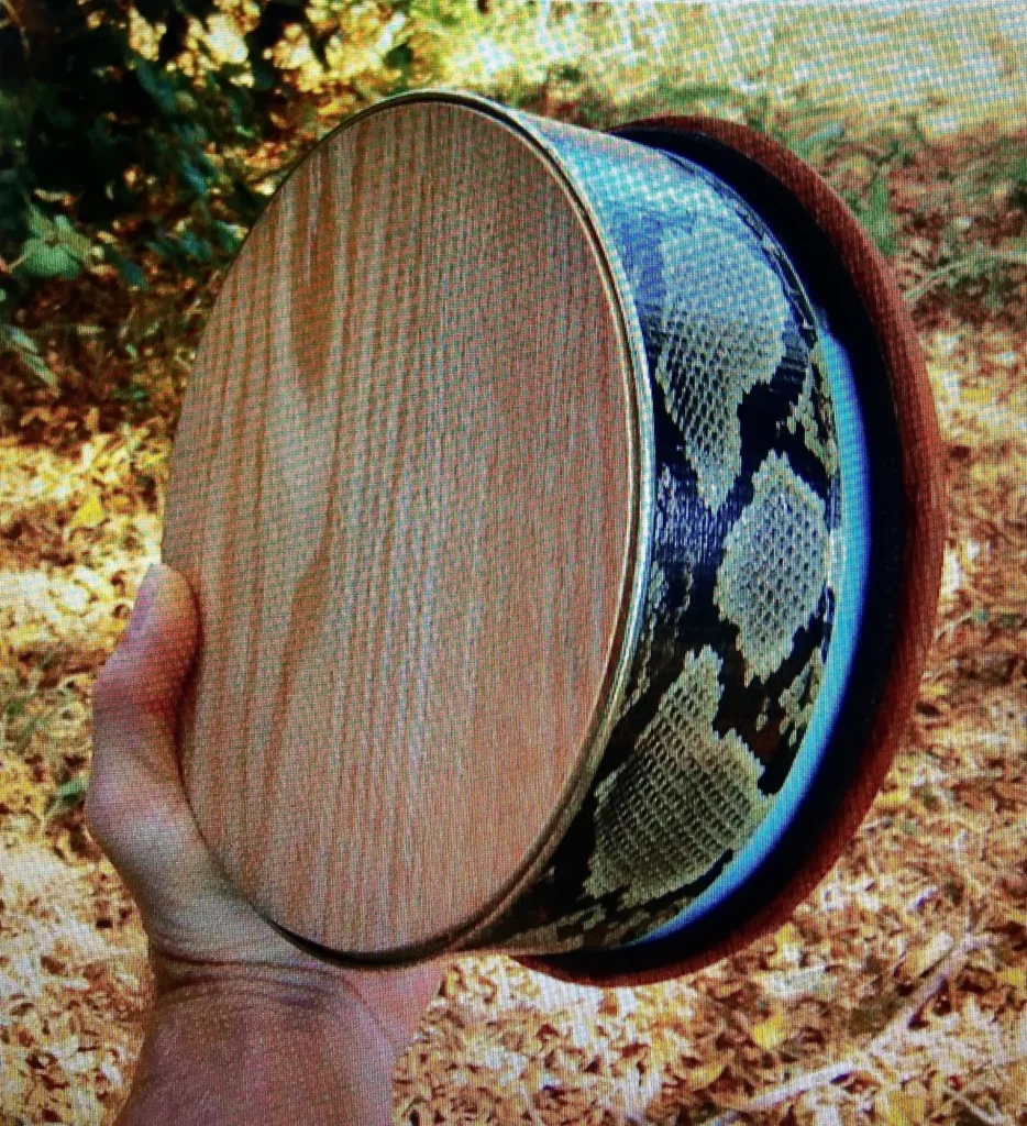 An individual playing the Ngoma, a traditional African musical instrument made of wood and python skin.