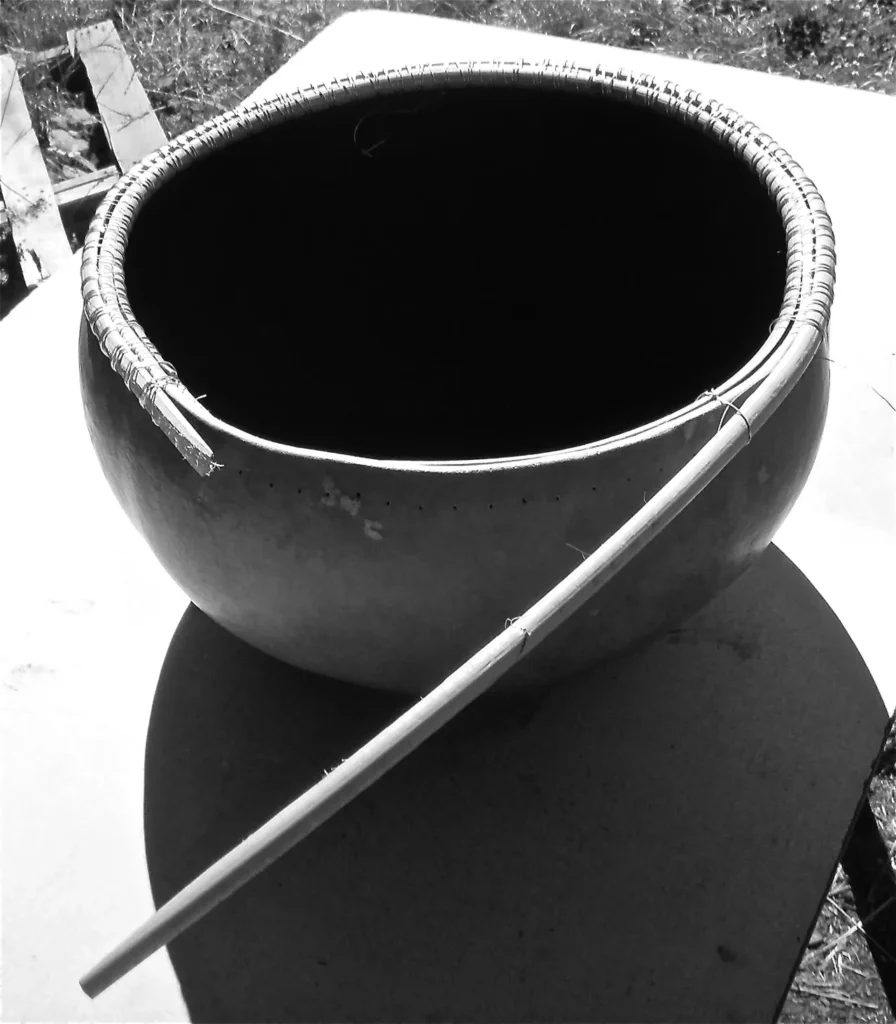 A black and white photo of a bowl with a stick in it, representing Ngoma - African Music.