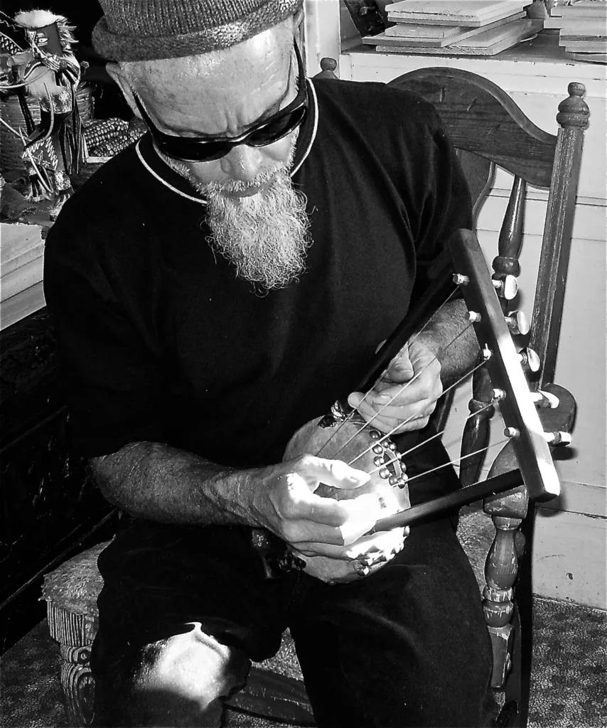 A black and white photo of a man playing a Kalimba, a musical instrument.