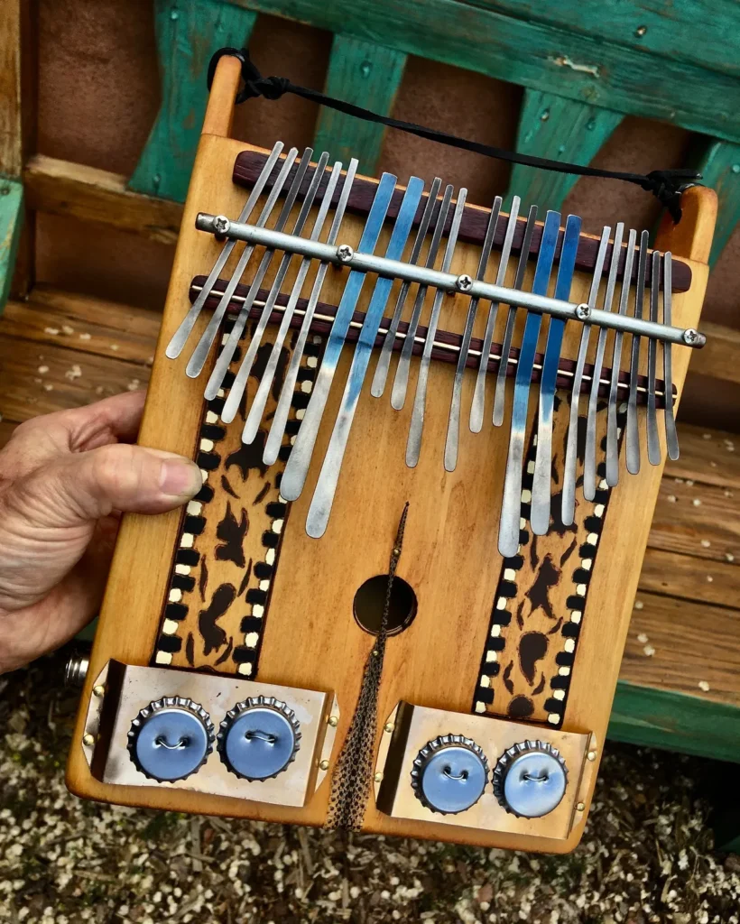 A person is holding up a lamellaphone, a wooden instrument.