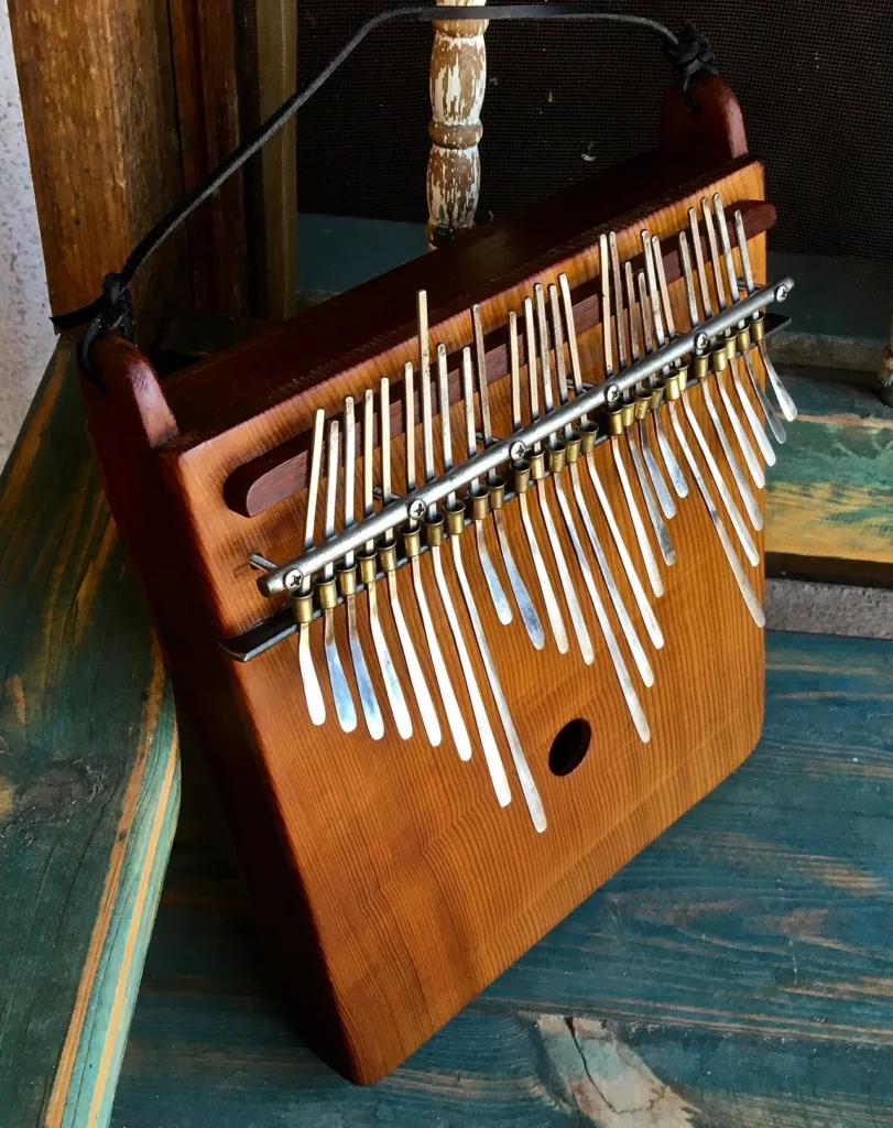 A wooden ukulele, a Kongoma percussion instrument, is sitting on top of a wooden table.