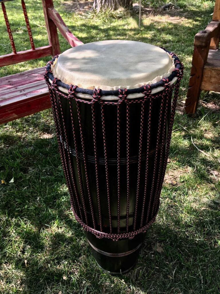 A djembe and Ilimba sitting on a bench in the grass.