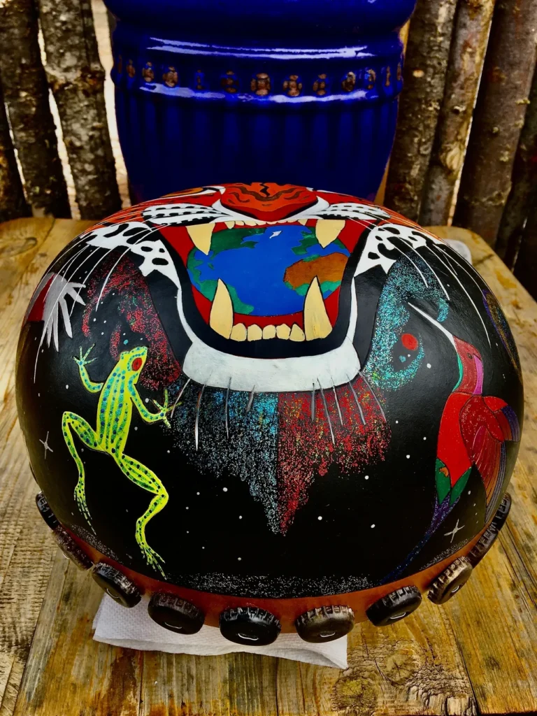 A painted drum with a tiger and frog on it, inspired by African folk art.