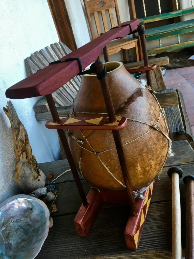 A wooden pot, crafted into a gourd instrument, sitting on a wooden stand.