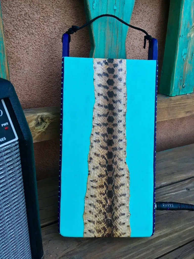 A blue box with a snake on it next to a speaker. The snake resembles a Gourd Instruments.