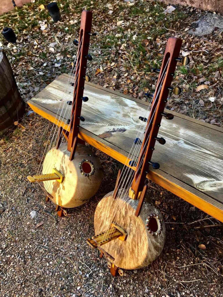 Two Ngoma guitars sitting on a wooden bench.