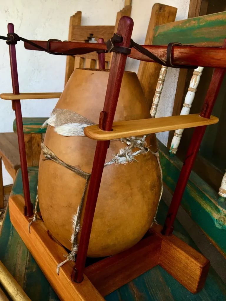 A wooden bowl on a wooden stand, designed to resemble traditional Gourd Instruments.