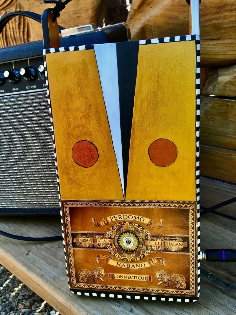 A gourd instrument sitting on a wooden table next to a guitar.