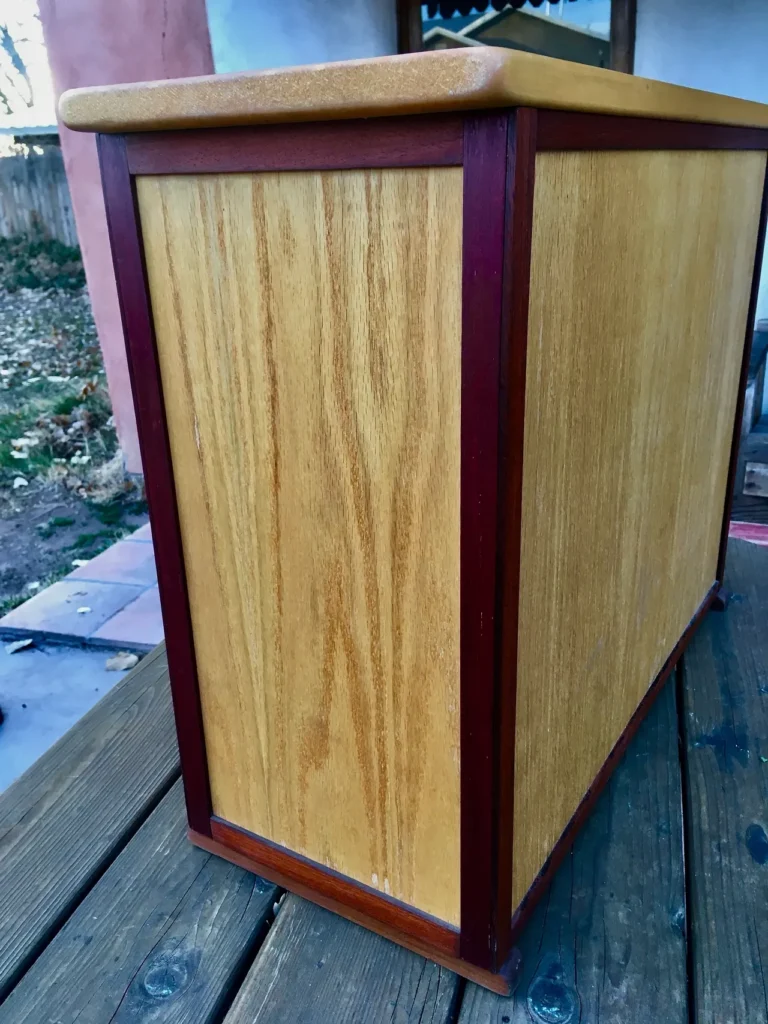 A wooden box, resembling a Kalimba, sitting on top of a wooden table.