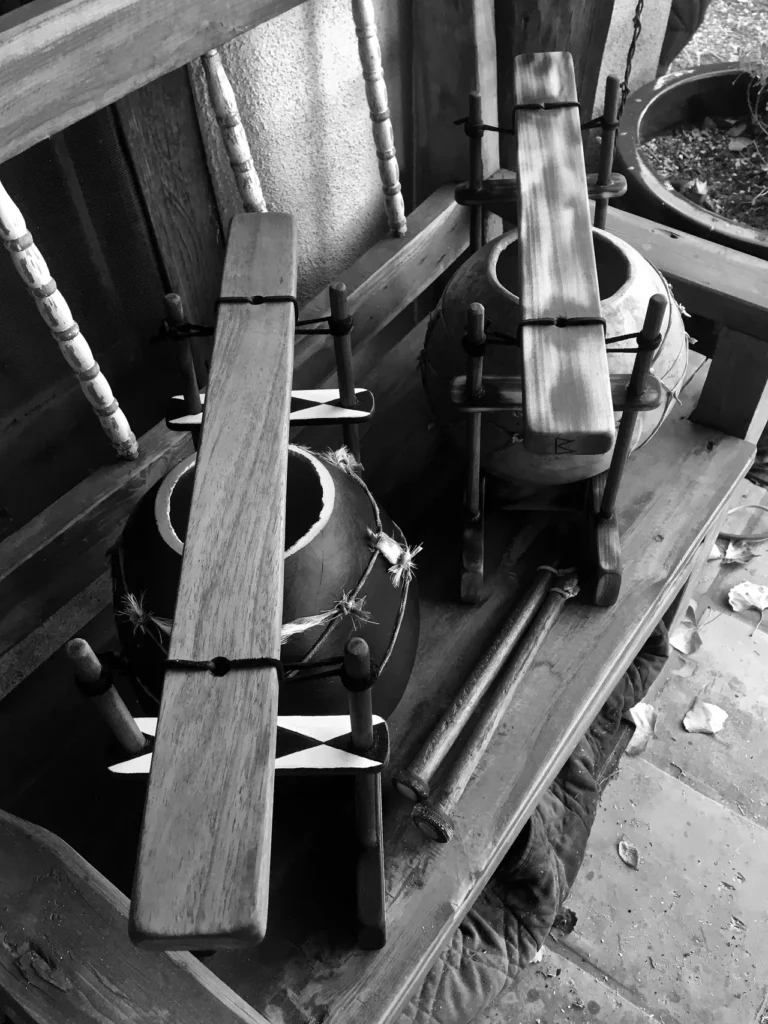 Two wooden bowls, resembling gourd instruments, sitting on a wooden bench.