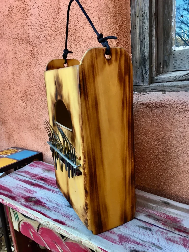 A wooden box, resembling a kalimba, sitting on a bench next to a window.