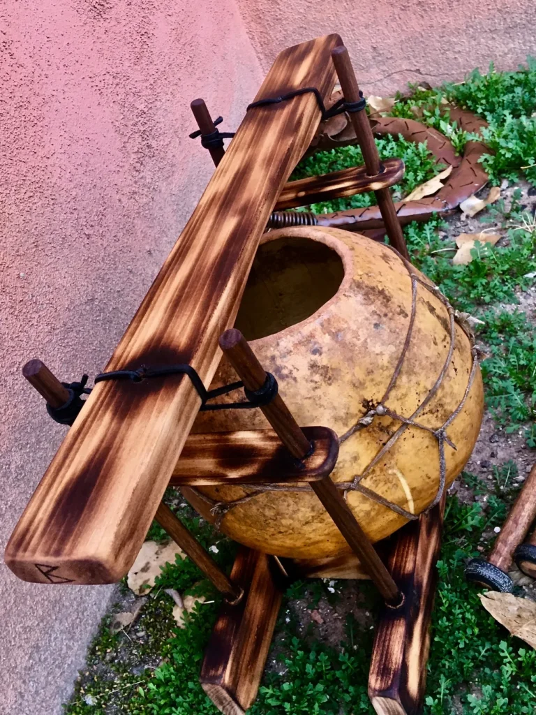 A wooden bowl enhanced with a wooden handle, reminiscent of traditional gourd instruments.