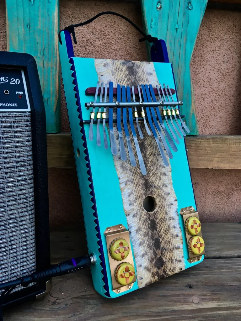 A blue acoustic guitar sitting on a wooden bench.