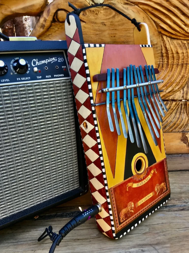 A Lamellaphone instrument is sitting on a wooden table next to an amp.