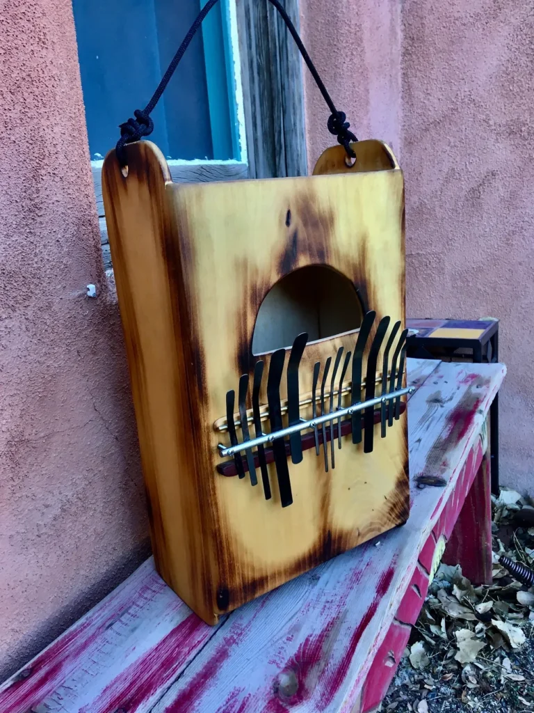 A wooden box, resembling a Kalimba, sitting on a bench next to a window.