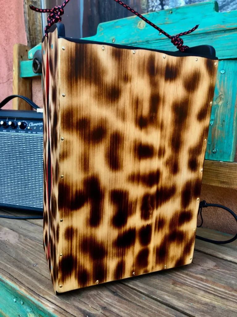 A wooden box with a leopard print, reminiscent of an African drum, sits on a wooden deck.