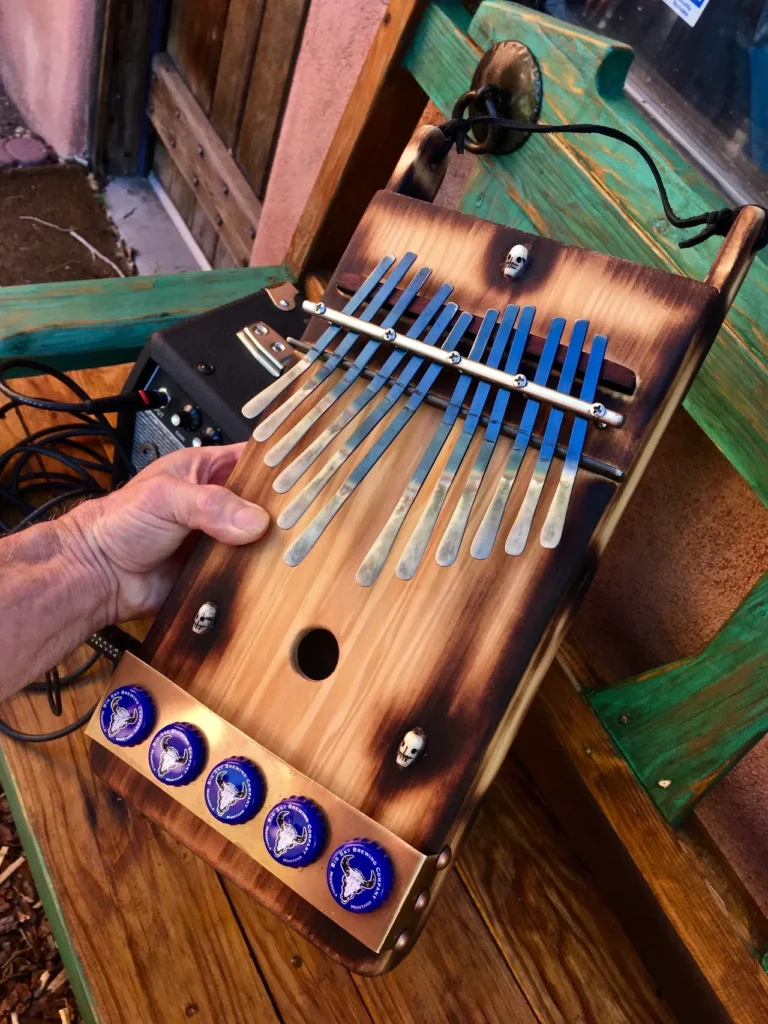 A person is holding a gourd lamellaphone on a wooden table.