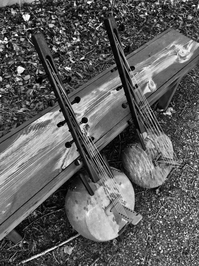 A black and white photo of a wooden bench with two guitars on it, capturing the essence of Ngoma music from Africa.