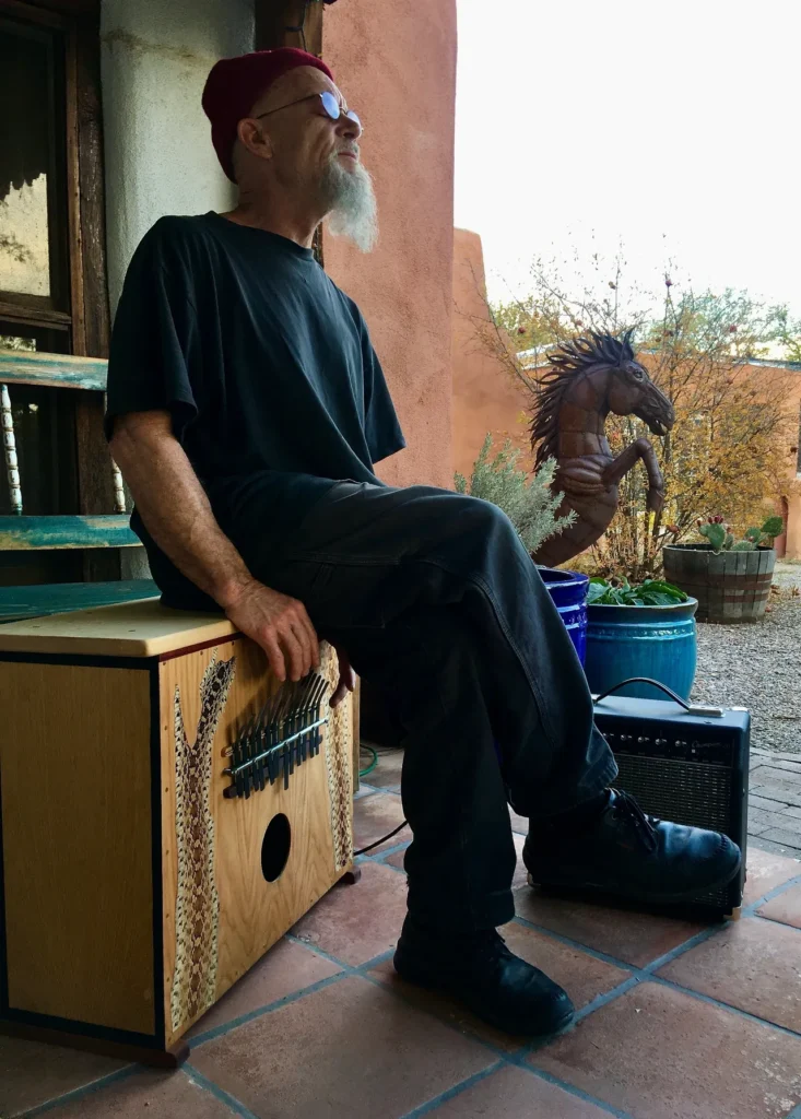 A man sitting on a wooden box, playing a Kalimba