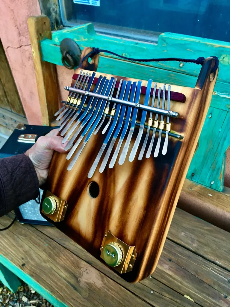 A person playing a lamellaphone on a wooden bench.