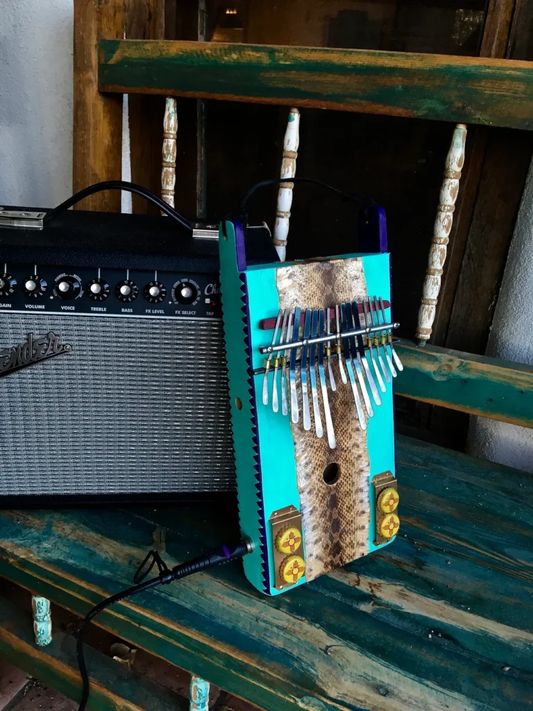 A gourd instrument and a guitar sitting on a wooden bench.