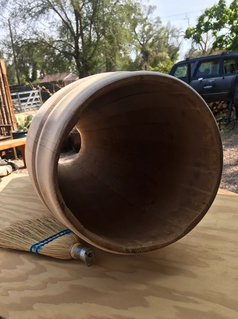 A wooden pipe made of Ilimba wood sitting on top of a Kongoma wooden table.