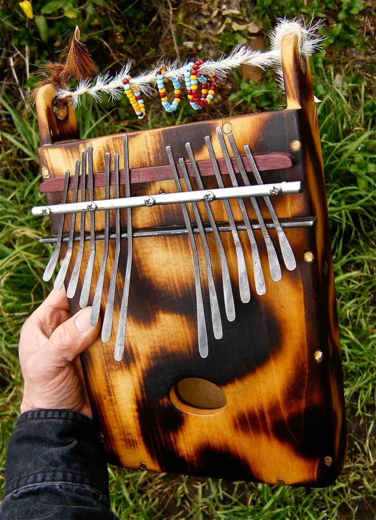 A person is holding a wooden ukulele in their hand while playing Ngoma, an instrument commonly used in African music.