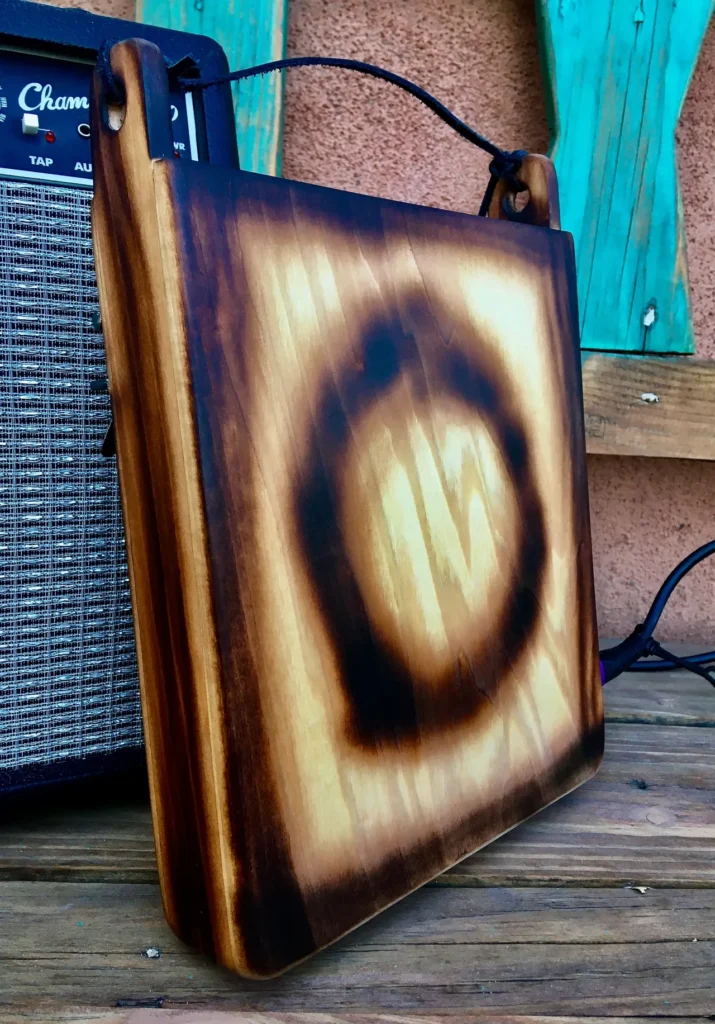 A wooden box with a guitar amplifier sitting on top of it, showcasing the harmonious blend of Gourd Instruments and Lamellaphone.