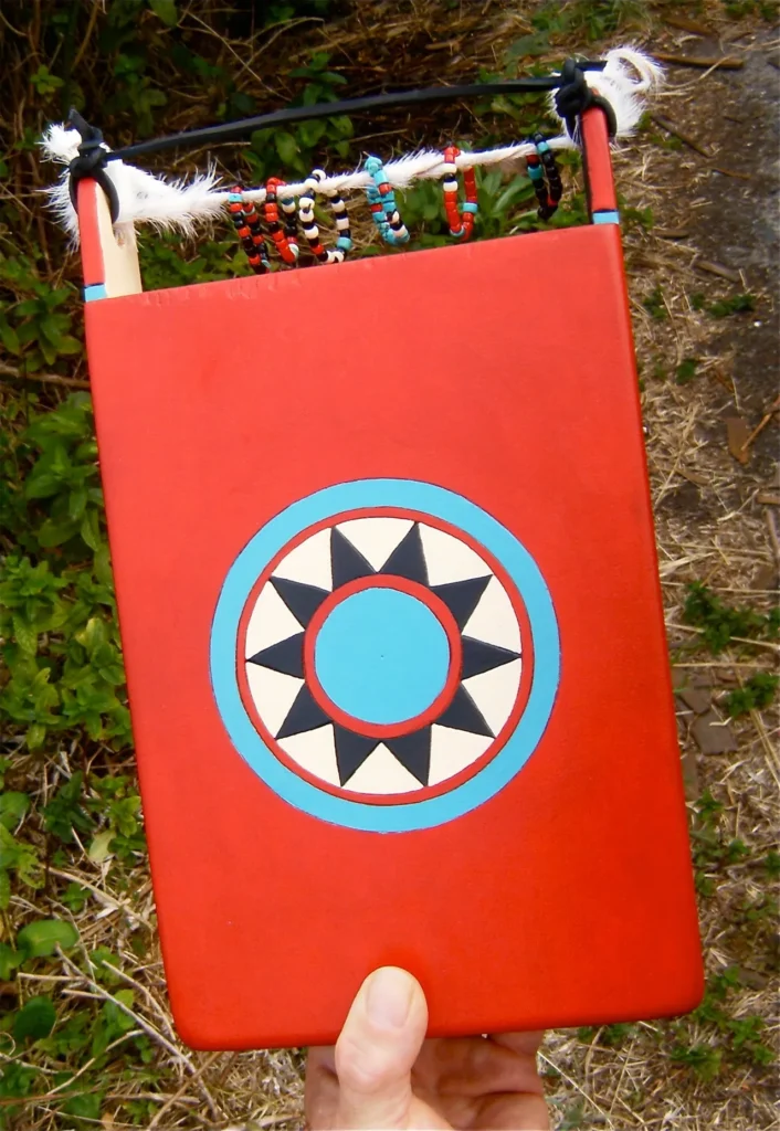 A person is holding a red book with an African Sun on it.