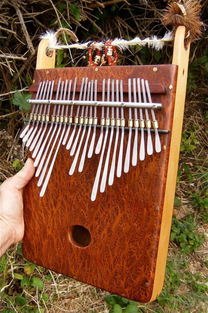 A person holding a Marimbula, a wooden instrument with a lot of tines.