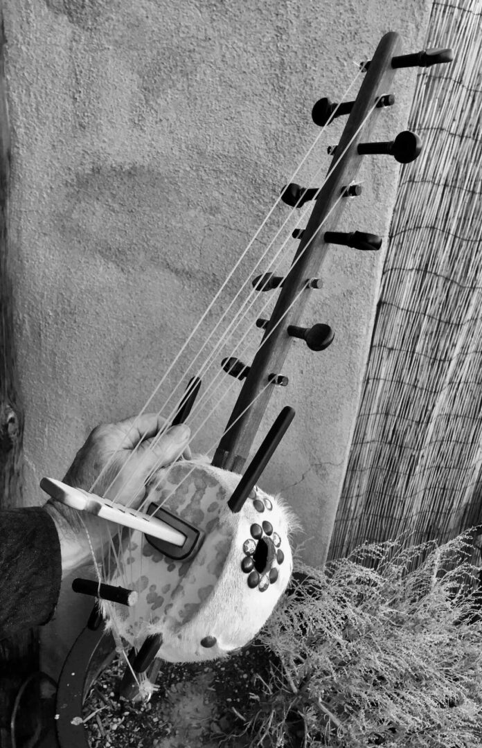 A black and white photo of a person playing Ngoma, an African musical instrument.