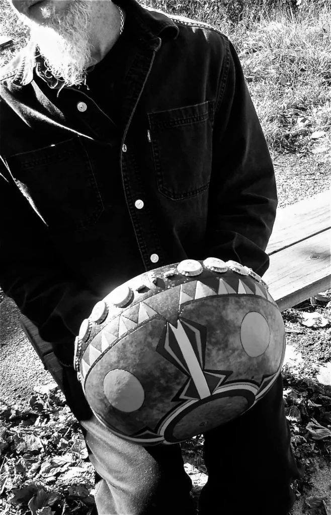 A black and white photo of a man holding a Ngoma.