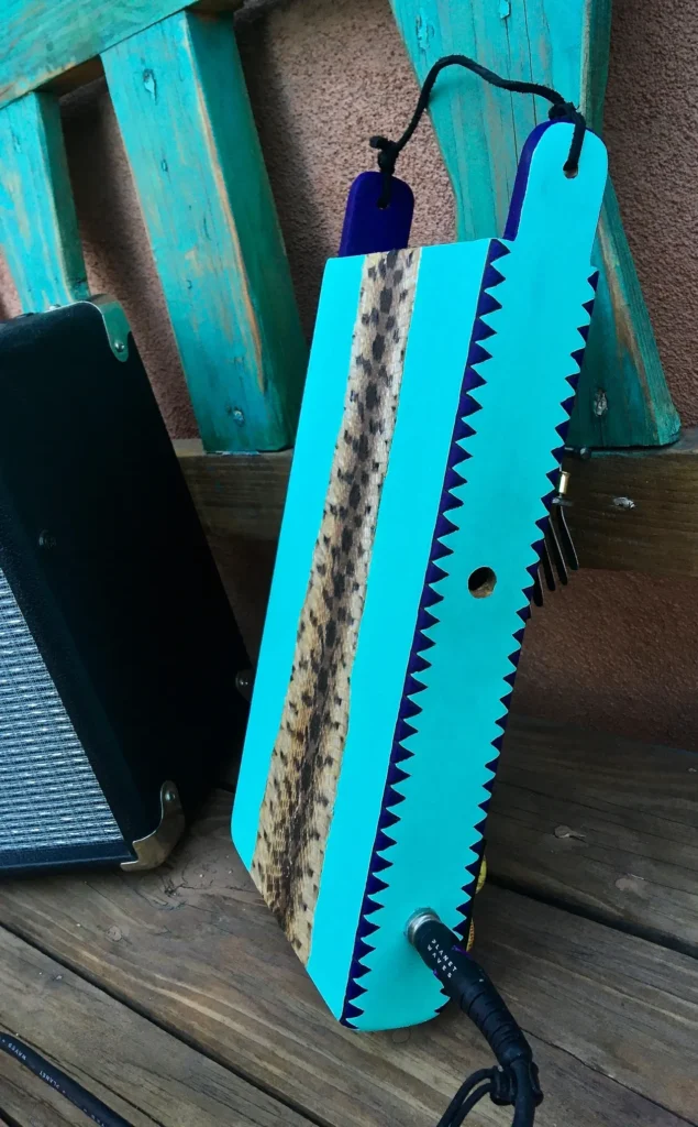 A blue guitar with a wooden case sitting on a wooden bench.