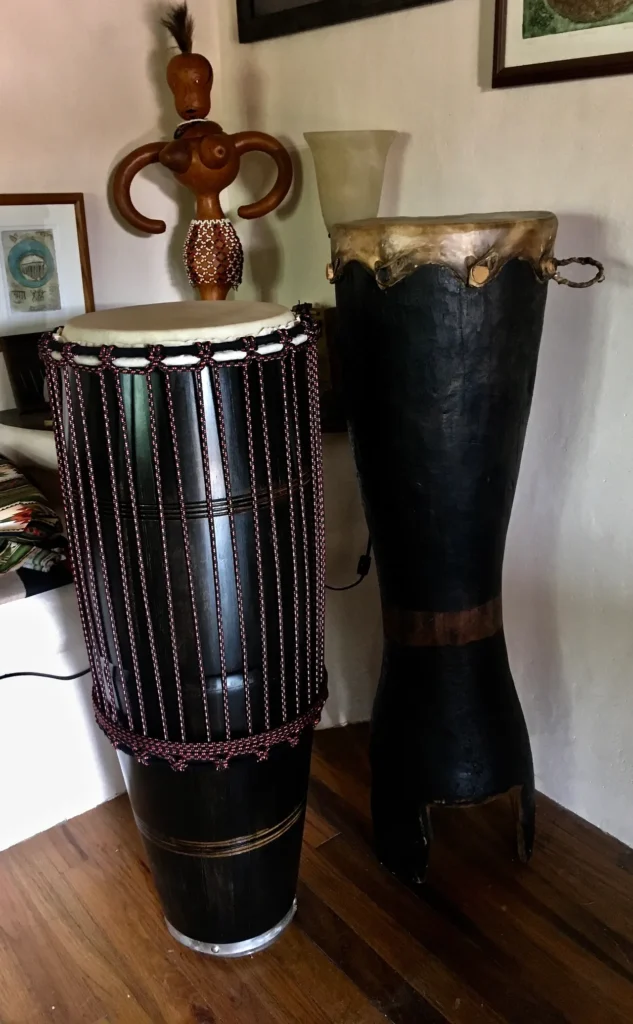 Two Kongoma djembes sitting on a wooden floor in a room.