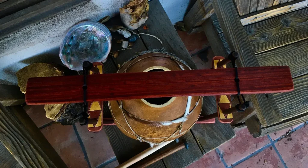 A wooden bowl, resembling a unique gourd instrument known as a lamellaphone, is delicately placed on a wooden table.