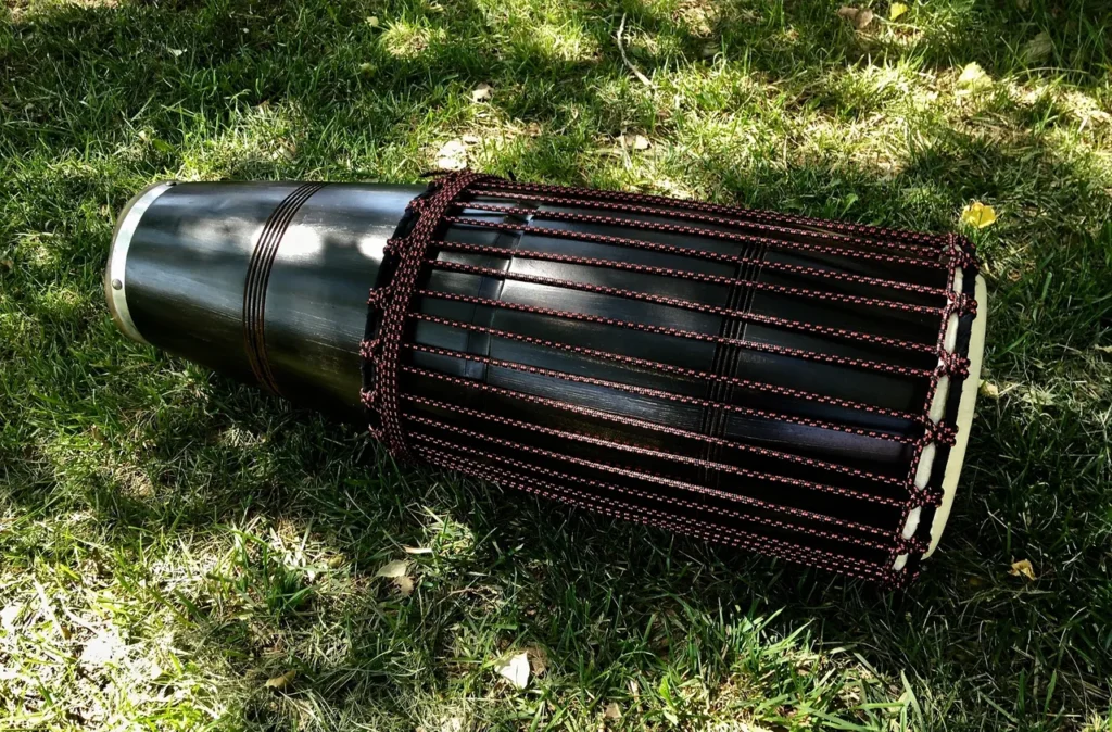 An Ilimba drum sitting on the ground in the grass.