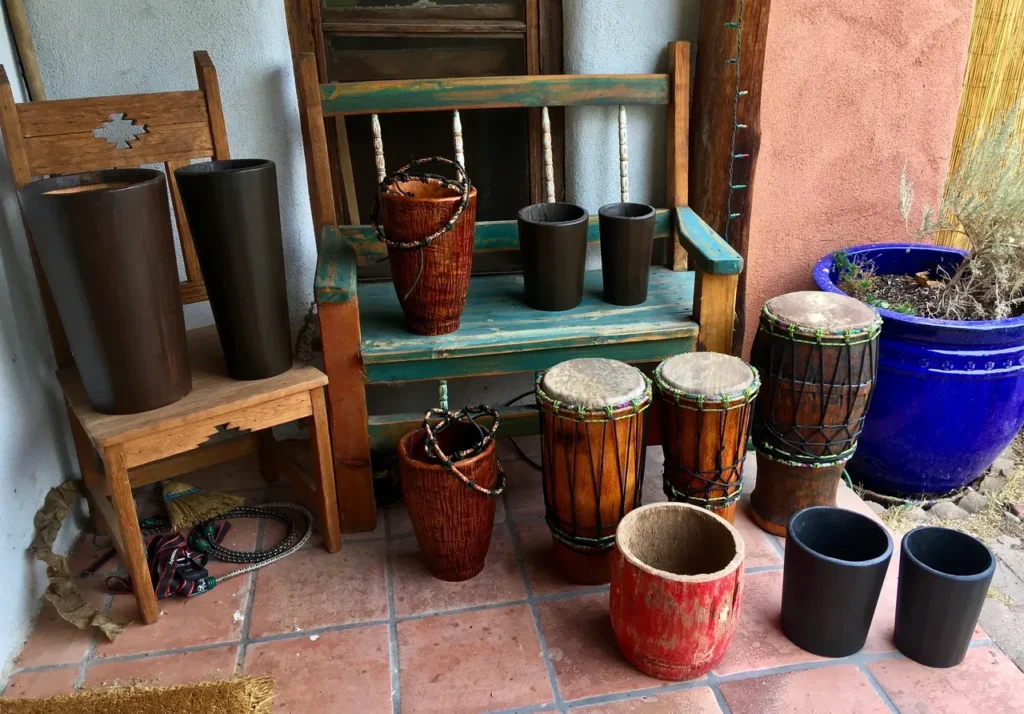 A wooden bench sits next to a set of drums, including an Ilimba drum.