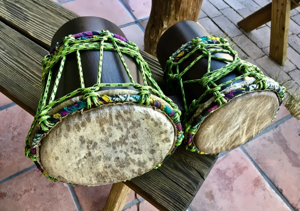 Two wooden drums, resembling African harps, sitting on a wooden bench.