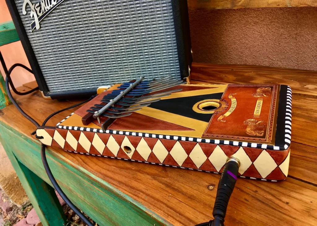 A gourd instrument and a lamellaphone placed in a wooden box on a wooden table.