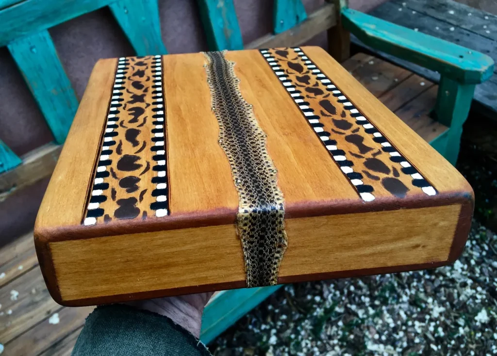 A person holding a Lamellaphone, a wooden box with a pattern on it, used in Gourd Instruments.